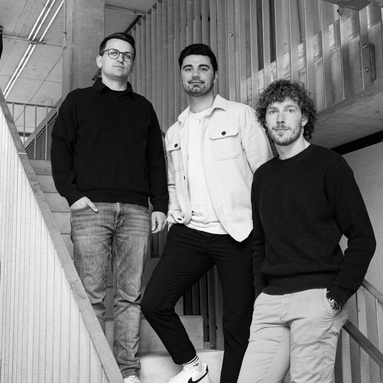 Drei Männer stehen auf einer Treppe in schwarz-weiß