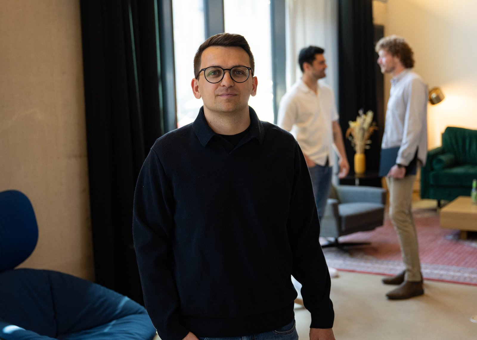 Mann in Bewegung im Vordergrund, zwei Männer unterhalten sich im Hintergrund.