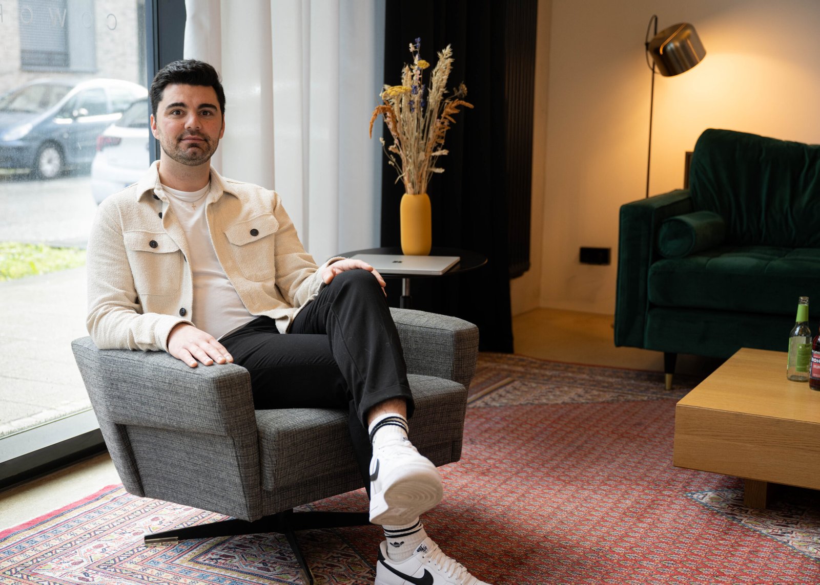 Ein Mann sitzt im Büro auf einem Sessel und schaut die Kamera an.