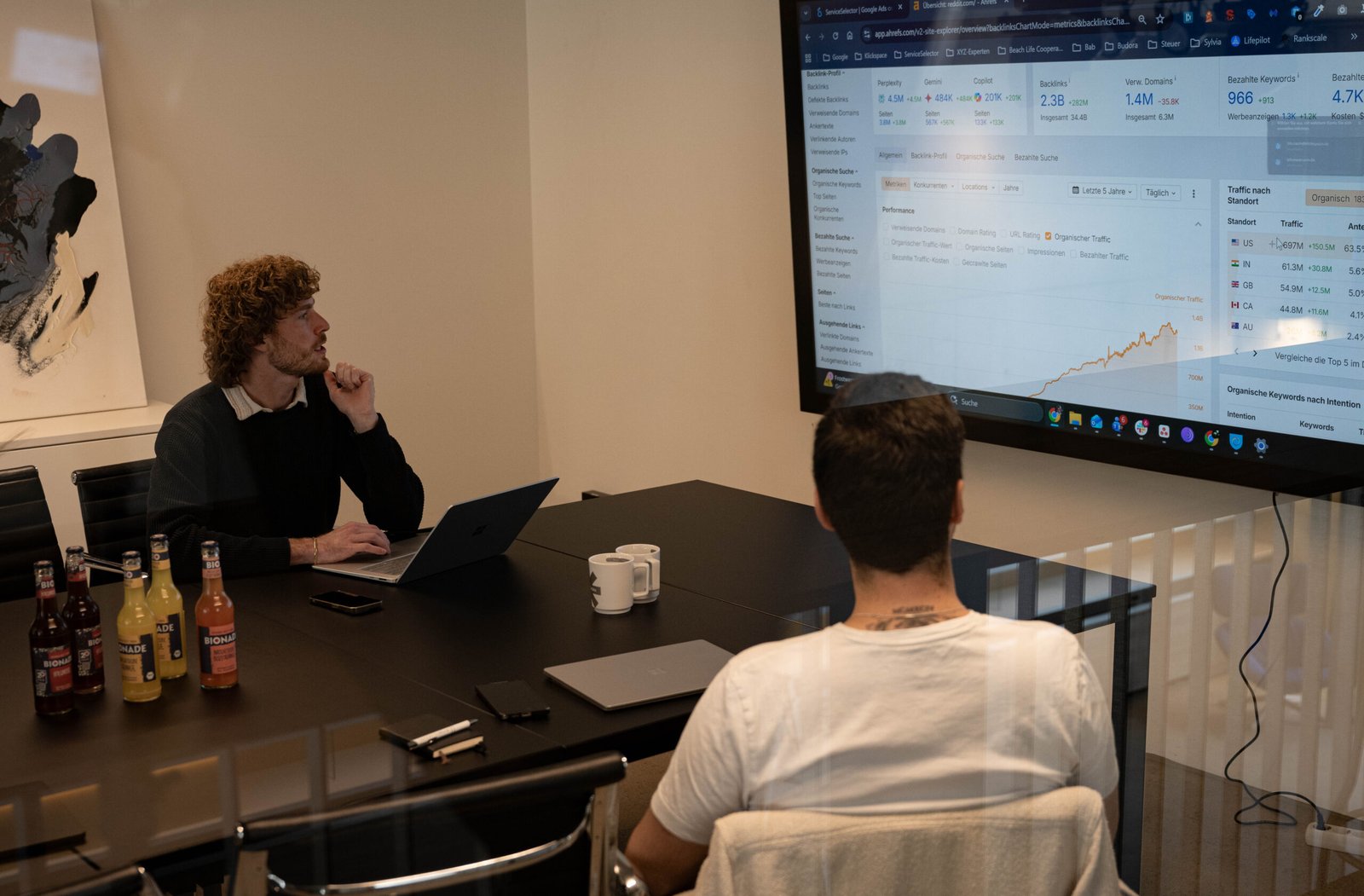 Zwei Männer sitzen im Meetingraum und schauen auf Online Marketing Analysen